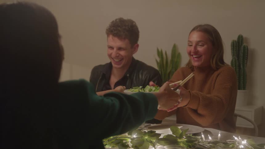Smiling friends share a salad during dinner