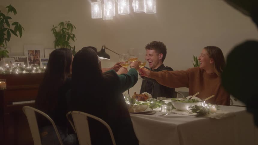 Friends raise glasses in a cheerful toast at a dinner table