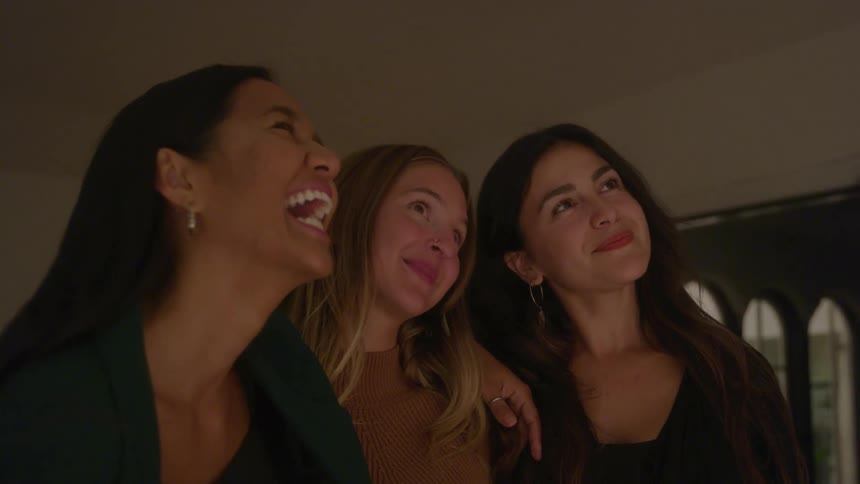 Three women stand together talking