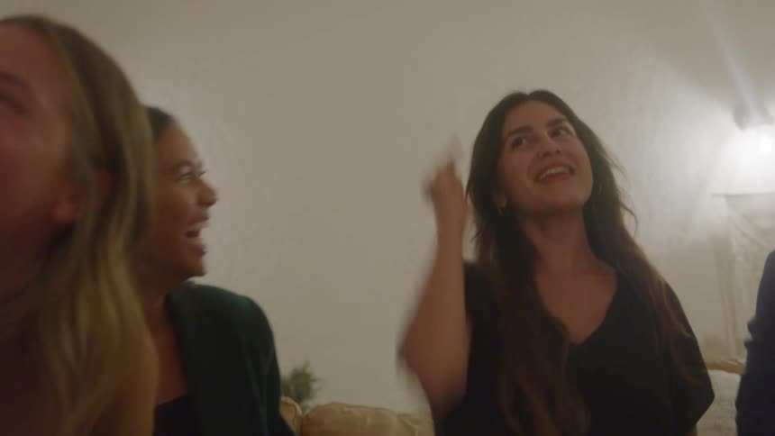 A group of friends on a couch laughing and playing in an animated fashion