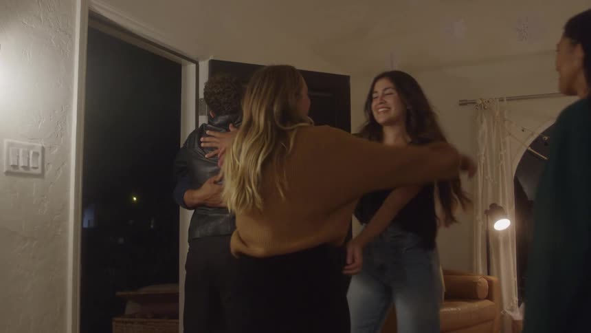 People share warm hugs at the entrance of a christmasdecorated home