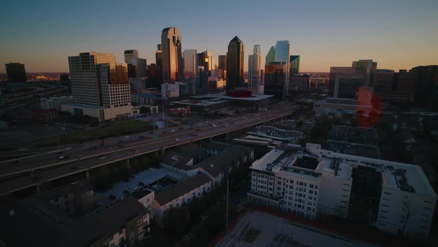 Aerial view of city skyline with highways in foreground at sunset