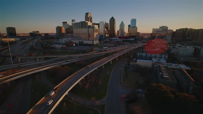 Elevated highways cross the city with skyscrapers in the background at sunset