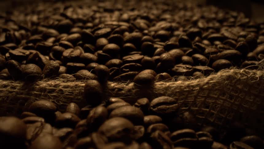 Coffee beans scattered over a rustic burlap sack