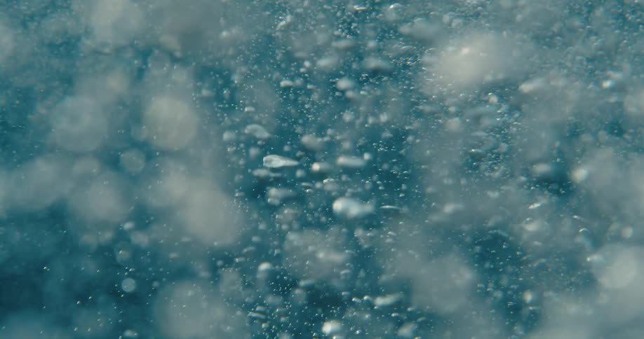 Based on the images from the video a closeup shot shows a lot of bubbles in clear water the bubbles are moving and rising in the water