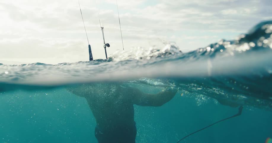 Based on the images from the video a closeup shot shows a persons head partially submerged in the ocean with a surfboard and what appears to be kiteboarding equipment below the surface the persons body is seen swimming and moving through the water