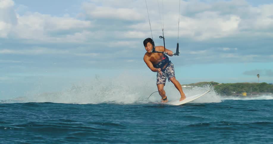 The man spins around on the surfboard while kite surfing