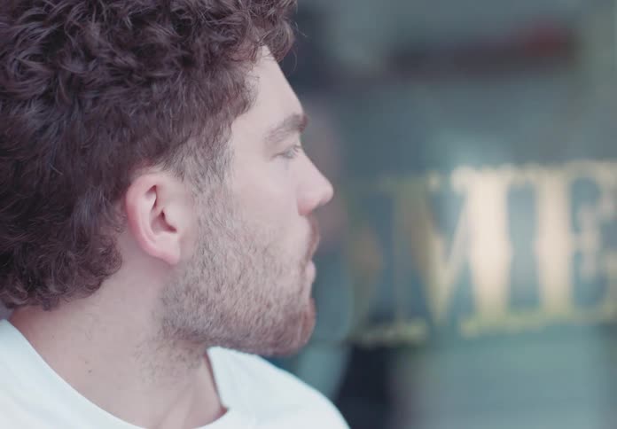 Man with short beard looks to the side in an outdoor setting