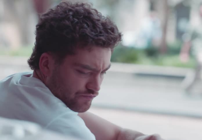 A man sips coffee by the window in soft daylight