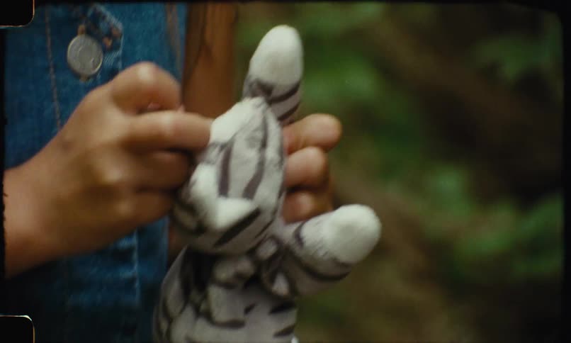 A young girl holds and plays with a stuffed animal cat with stripes