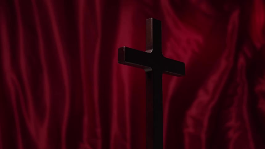 Wooden cross positioned against a red background