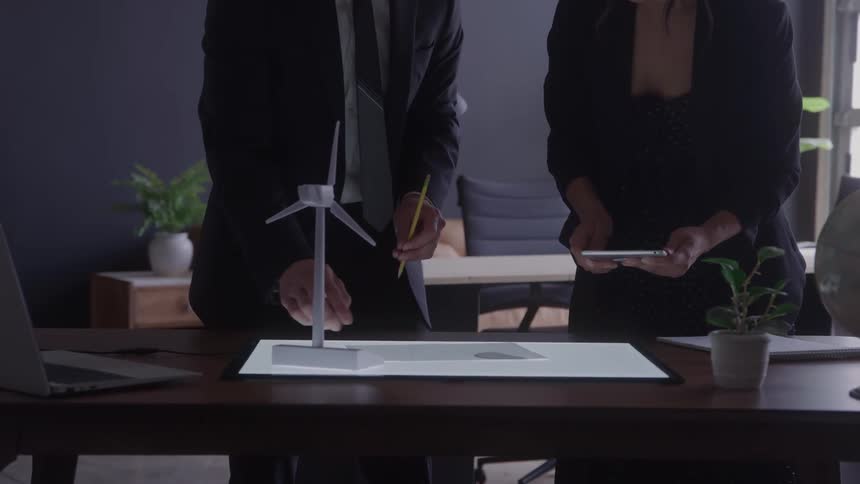 Two coworkers in the office are examining a document and talking