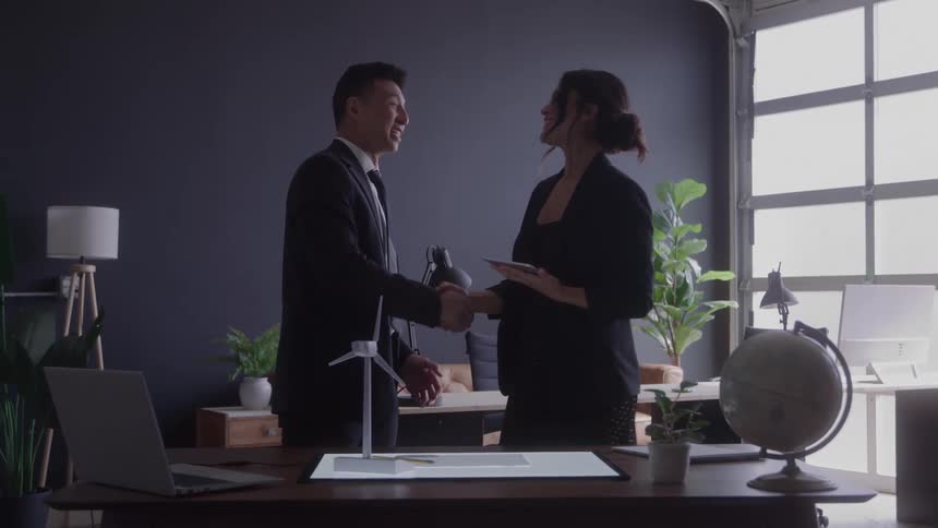Two professionals shake hands in a modern office
