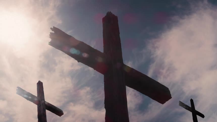 Wooden crosses against the sky with the sun shining through the clouds