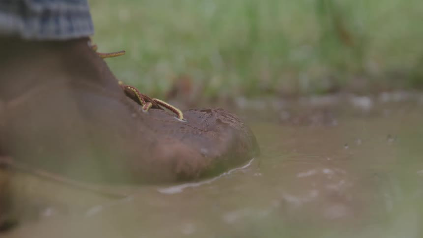 A person steps into muddy water while walking outdoors