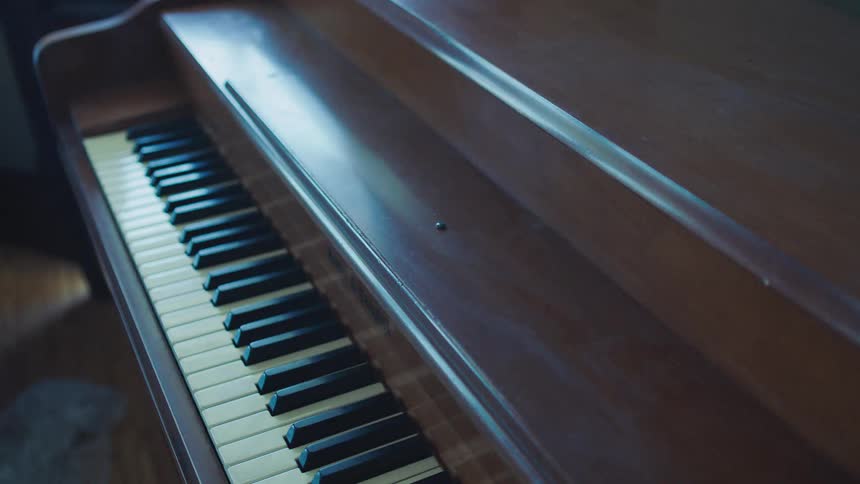 A piano is being unwrapped under soft light indoors