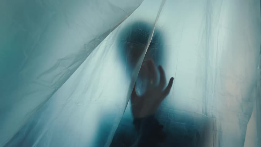 Silhouette of a person behind a translucent blue fabric