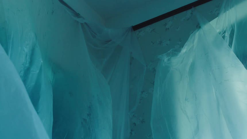 A room covered in plastic sheeting suggesting a renovation or abandoned space