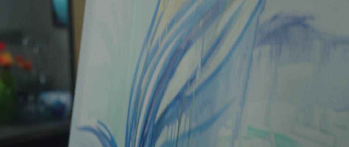 An artist painting on a canvas inside a studio at midday