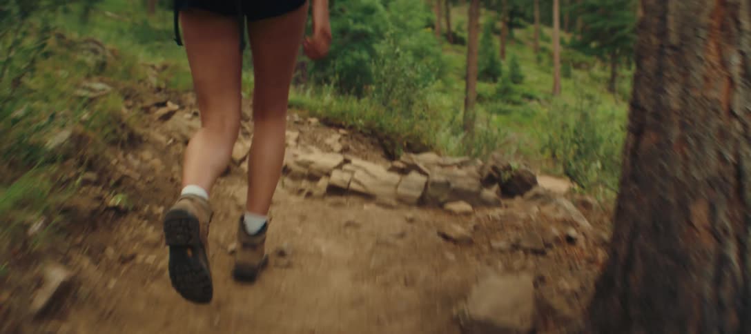 Person walking along a forest trail with a gray backpack