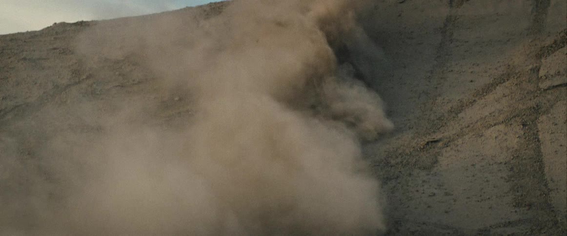 A motorcycle speeds up a sand dune