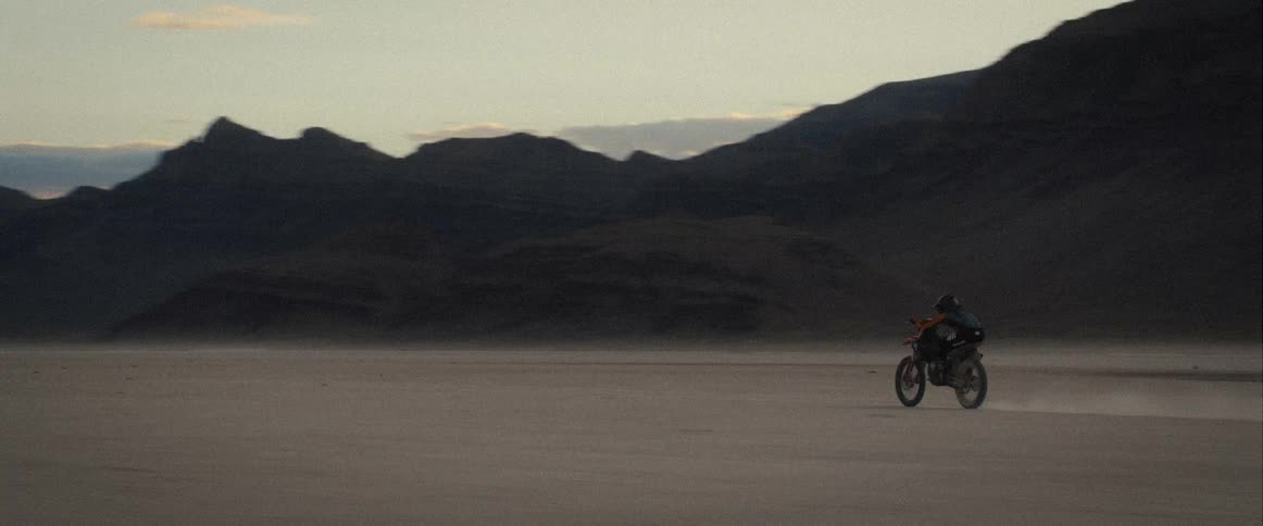 A person speeds through the desert on their dirt bike