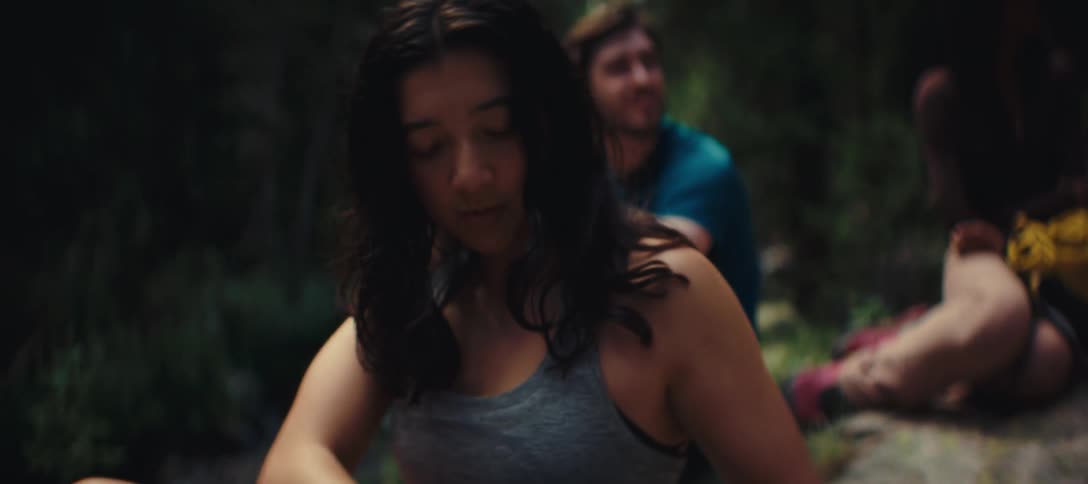 A hiker checks her backpack while resting on a forest trail