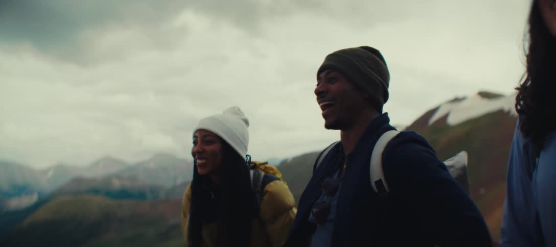 Three people smiling while enjoying the view on a mountain hike