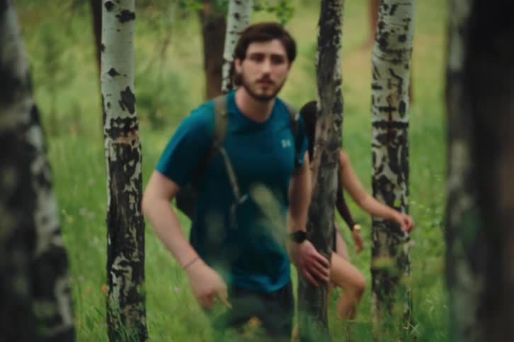 Friends hike through a forest with backpacks
