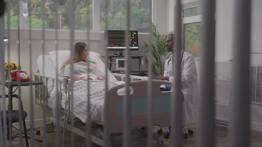 A woman in a hospital bed talking to a doctor who is sitting near her