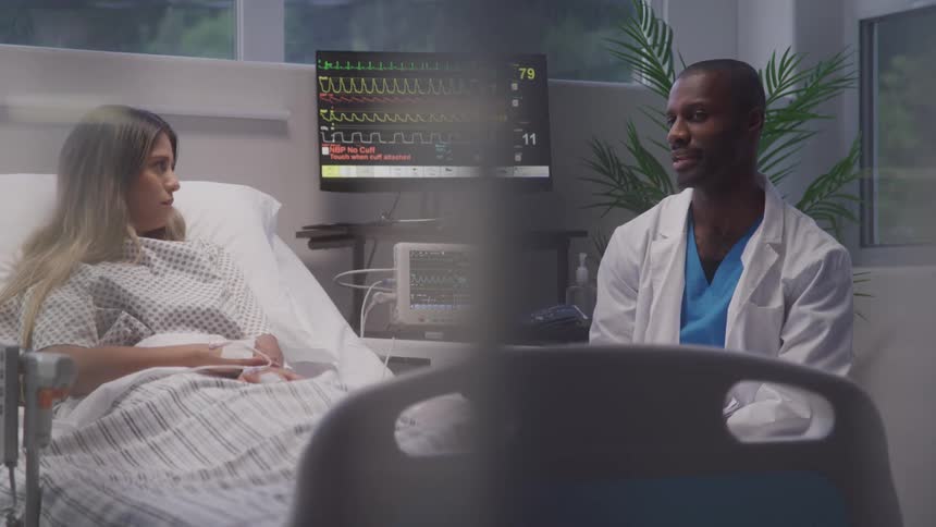 A doctor talks to a patient in a hospital room