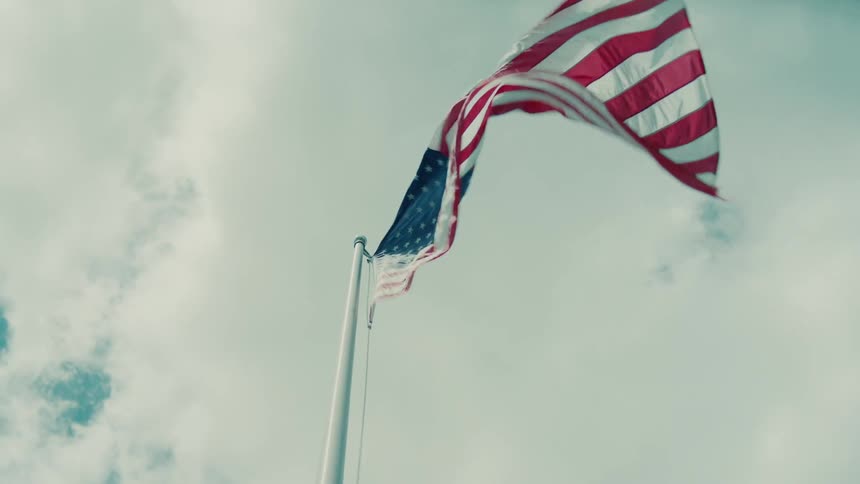 An american flag waves against a cloudy sky