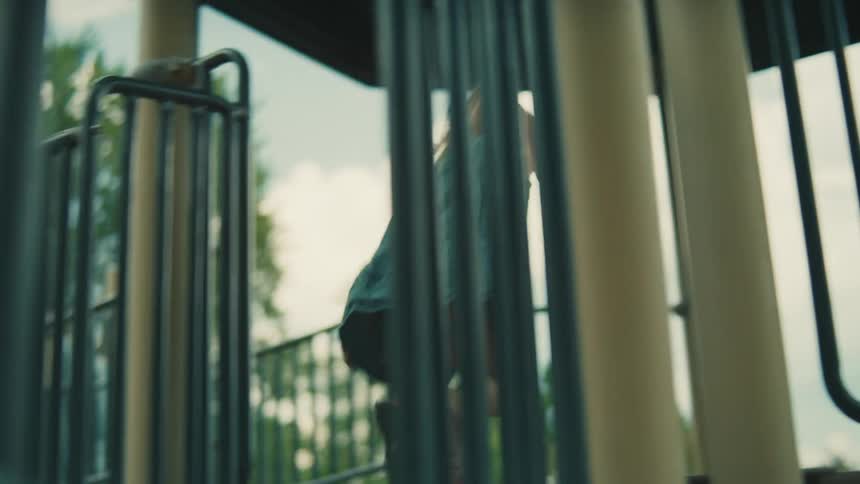 Blonde girl plays on the playground equipment on a summer day