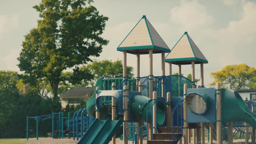 An empty colorful playground on a cloudy day focusing on the large blue and green play structure with no one using it
