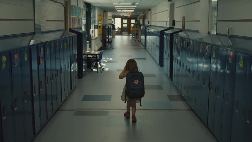 The little girl walks through the school hallway alone