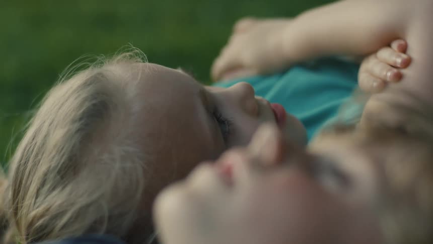 Two kids talking together while lying in the park