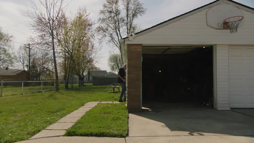 A man walks down a sidewalk and then enters his dark garage