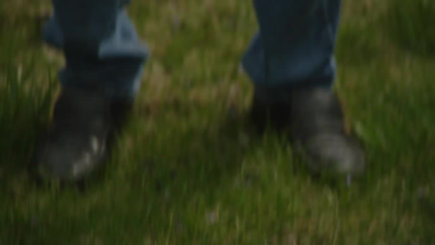 An elderly man making a golf putt on his backyard lawn