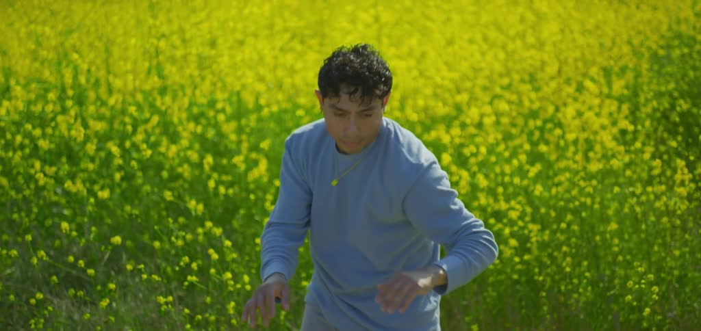 Man dancing in front of a field with yellow flowers