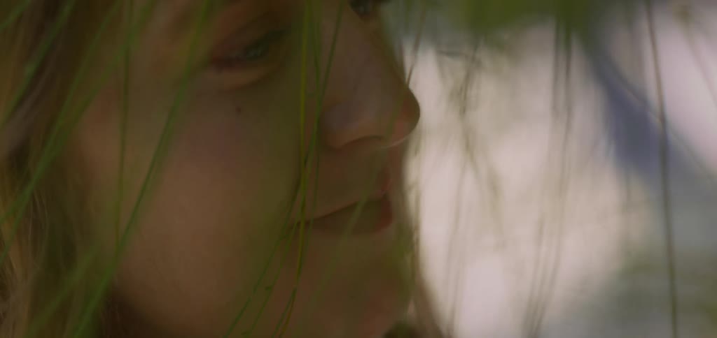 Blonde woman among green leaves with happy expression