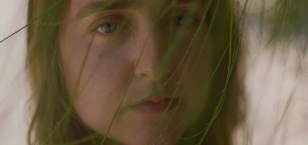 Young woman with blue eyes among green leaves