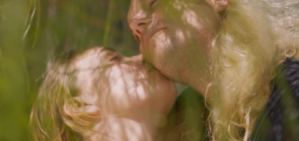 Woman kissing a man while they are under a tree