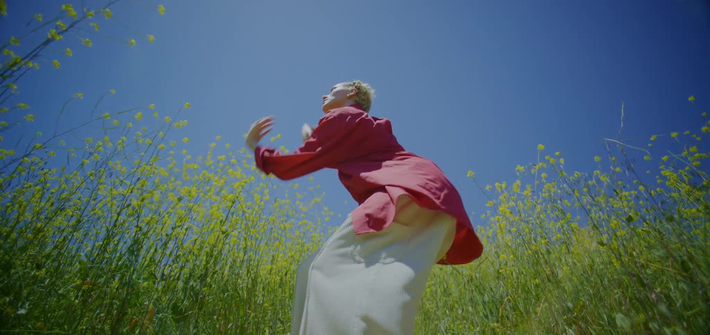 Blonde woman dancing in a field of yellow flowers