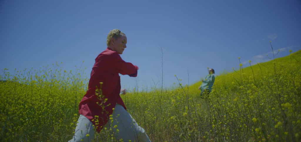 Two women dancing in a field with yellow flowers