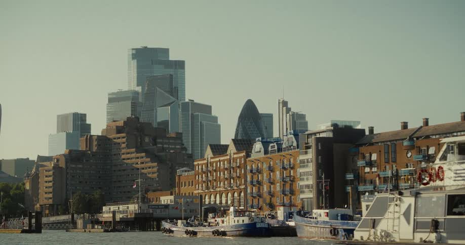 Boats docked on the river in front of historic buildings and modern skyscrapers in the city of london