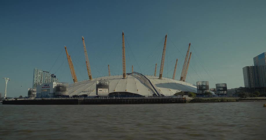 A wide shot from the water showing a stadium with its large dome and yellow support pylons