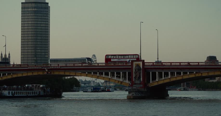 Red bus crosses vauxhall bridge over the river thames