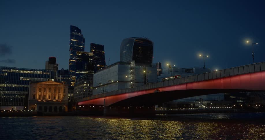Illuminated bridge reflects on the thames waters at dusk in london