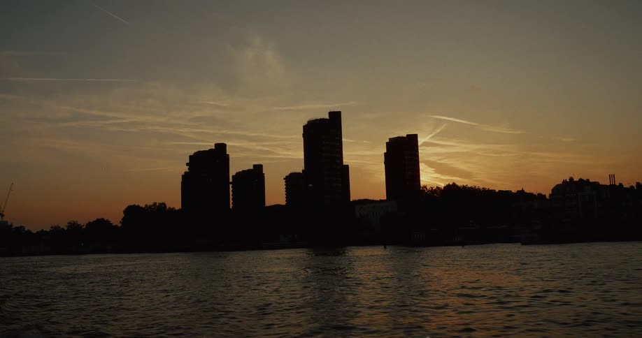 Metropolitan city skyline across a flowing sea outdoors at sunset