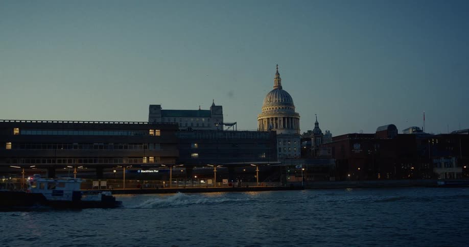 A boat drives down the river in front of the citys skyline, St Pauls Cathedral in the distance